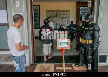 Bogor, Indonésie. 14 février 2024. Un fonctionnaire électoral portant le costume de super-héros Batman monte la garde lors des élections présidentielles et législatives indonésiennes dans un bureau de vote à Bogor, Indonésie, le 14 février 2024. (Photo par Andi M Ridwan/INA photo Agency/SIPA USA) crédit : SIPA USA/Alamy Live News Banque D'Images