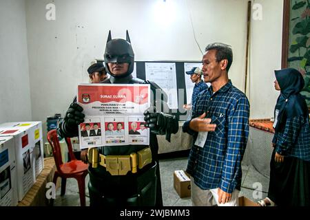 Bogor, Indonésie. 14 février 2024. Un fonctionnaire électoral portant le costume de super-héros Batman tient un bulletin de vote lors des élections présidentielles et législatives indonésiennes dans un bureau de vote à Bogor, Indonésie, le 14 février 2024. (Photo par Andi M Ridwan/INA photo Agency/SIPA USA) crédit : SIPA USA/Alamy Live News Banque D'Images