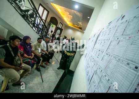 Bogor, Indonésie. 14 février 2024. Un responsable électoral portant le costume de super-héros Batman vérifie une liste de candidats lors des élections présidentielles et législatives indonésiennes dans un bureau de vote à Bogor, Indonésie, le 14 février 2024. (Photo par Andi M Ridwan/INA photo Agency/SIPA USA) crédit : SIPA USA/Alamy Live News Banque D'Images