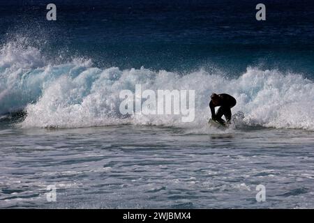 Surfeur sur le point de se lever sur une planche de surf, Fuerteventura prise novembre 2023 Banque D'Images