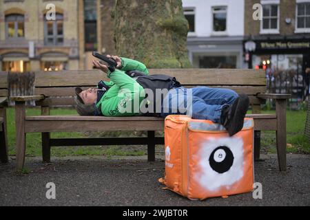 14 février 2024 : un transporteur Uber Eats Food fait une pause entre deux emplois à Islington Green, Londres. Deliveroo et Uber Eats courriers font grève ce soir entre cinq et dix heures pour obtenir de meilleures conditions de travail et de salaire. Banque D'Images