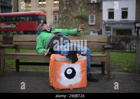 14 février 2024 : un transporteur Uber Eats Food fait une pause entre deux emplois à Islington Green, Londres. Deliveroo et Uber Eats courriers font grève ce soir entre cinq et dix heures pour obtenir de meilleures conditions de travail et de salaire. Banque D'Images