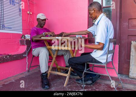 Deux dominicains plus âgés jouant un jeu de dominos sur le porche d'un bâtiment à Puerto Plata, République dominicaine. Dominos est le passe-temps national i. Banque D'Images