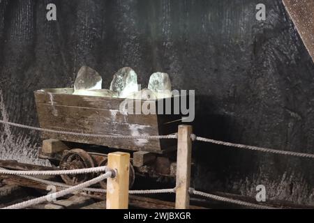 Vieux wagon de mine avec des pierres de sel illuminées dans la mine de sel de Turda, Roumanie Banque D'Images