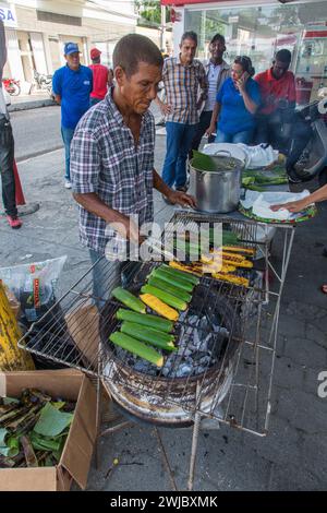 Un homme cuisinant des tamales dominicaines sur un grill ouvert dans la rue à la Bani Mango Expo à Bani, République dominicaine. Banque D'Images