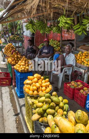 Trois personnes vendant des mangues dans un kiosque de fruits au bord de la route à Bani, en République dominicaine. Banque D'Images