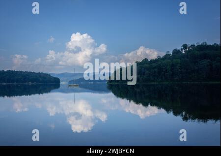 Lac bleu et ciel avec des nuages, reflet de forêt dans l'eau, Bieszczady, lac Solina, Pologne. Fin de l'été. Banque D'Images