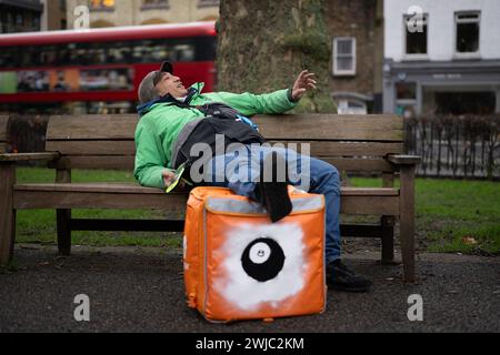 14 février 2024 : un transporteur Uber Eats Food fait une pause entre deux emplois à Islington Green, Londres. Deliveroo, et Uber Eats coursiers font grève ce soir entre cinq et dix heures pour obtenir de meilleures conditions de travail et de salaire. Banque D'Images