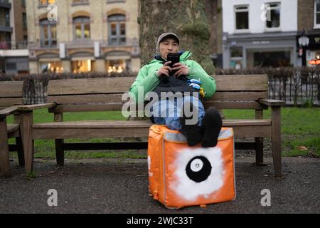 14 février 2024 : un transporteur Uber Eats Food fait une pause entre deux emplois à Islington Green, Londres. Deliveroo, et Uber Eats coursiers font grève ce soir entre cinq et dix heures pour obtenir de meilleures conditions de travail et de salaire. Banque D'Images