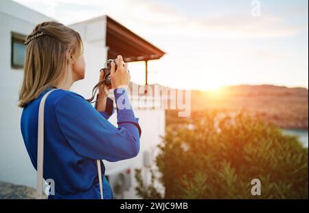 Une touriste prend des photos du coucher du soleil. Banque D'Images