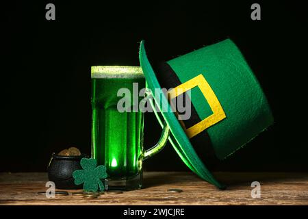 Verre de bière verte avec feuille de trèfle, chapeau de Leprechaun et pot plein de pièces de monnaie sur fond noir. Prog Célébration de la fête de Patrick Banque D'Images