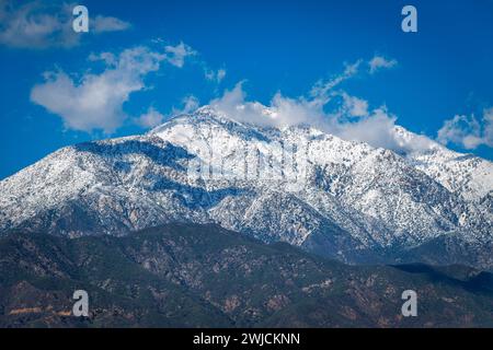 Première neige sur Ontario Peak dans la forêt nationale d'Angeles avec des nuages dispersés projetant des ombres sur le flanc de la montagne. Banque D'Images