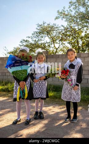 Écolière avec un bouquet de fleurs lors de son premier jour à l'école, région d'Issyk-Koul, Kirghizistan Banque D'Images