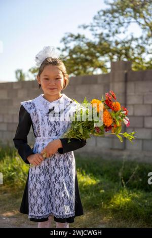 Écolière avec un bouquet de fleurs lors de son premier jour à l'école, région d'Issyk-Koul, Kirghizistan Banque D'Images