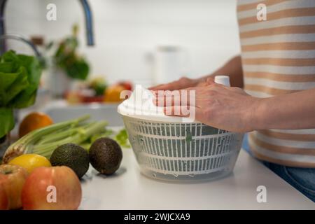 Cuisson d'un dîner sain frais rapide en préparant des épinards verts, du céleri dans un sèche-linge en plastique à la main. Banque D'Images