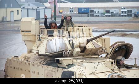 Drawsko Pomorskie, Pologne. 10 février 2024. Bre, cheerleader des commandants de Washington, lève les bras alors qu'elle fait un tour dans un char de combat principal M1A2 Abrams de l'armée américaine avec la 1re division blindée au Drawsko combat Training Center, le 10 février 2024 à Drawsko Pomorskie, dans la voïvodie de Poméranie occidentale, Pologne. La National Football League s'est associée à l'Armed Forces Entertainment dans le cadre de Pro Blitz 2024. Crédit : SPC. Trevares Johnson/US Army/Alamy Live News Banque D'Images