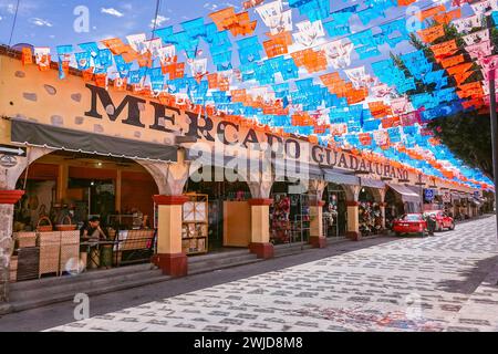 Des drapeaux picado en papier papel décorent la principale rue commerçante touristique de Calle Ezequiel Montes et le Mercado Guadalupano dans le quartier historique de Tequisquiapan, Querétaro, Mexique. Banque D'Images