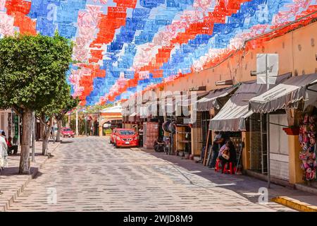 Des drapeaux picado en papier papel décorent la principale rue commerçante touristique de Calle Ezequiel Montes dans le quartier historique de Tequisquiapan, Querétaro, Mexique. Banque D'Images