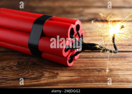 Bombe dynamite avec fusible allumé sur table en bois, gros plan Banque D'Images