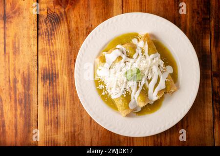 Enchiladas vertes. Plat mexicain typique fait avec une tortilla de maïs pliée ou roulée remplie de poulet râpé et recouverte de sauce verte épicée, cre Banque D'Images