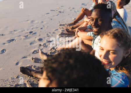 Divers amis profitent d'un coucher de soleil sur la plage Banque D'Images