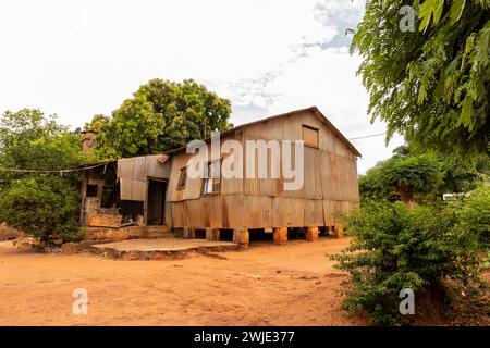 Ancienne maison revêtue de zinc de construction précaire élevée sur des fondations sur pilotis, composée de piliers en briques de terre construits au Mozambique Banque D'Images