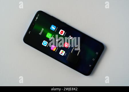 Ouzbékistan, Tachkent - 27 janvier 2024 : un cadenas couché sur l'écran d'un téléphone portable avec des icônes de médias sociaux dessus. Le concept de limitation du temps sur la socia Banque D'Images