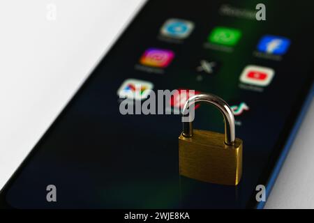 Ouzbékistan, Tachkent - 27 janvier 2024 : un cadenas couché sur l'écran d'un téléphone portable avec des icônes de médias sociaux dessus. Le concept de limitation du temps sur la socia Banque D'Images