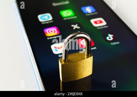 Ouzbékistan, Tachkent - 27 janvier 2024 : un cadenas couché sur l'écran d'un téléphone portable avec des icônes de médias sociaux dessus. Le concept de limitation du temps sur la socia Banque D'Images