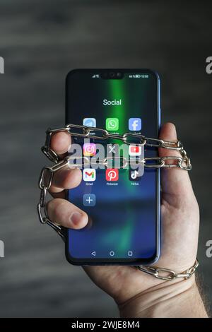 Ouzbékistan, Tachkent - 27 janvier 2024 : chaîne à portée de main avec téléphone mobile avec icônes de réseau social. Concept de limitation du temps sur les réseaux sociaux, addic Banque D'Images