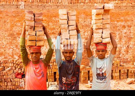 Dhaka, Dhaka, Bangladesh. 15 février 2024. Les ouvriers portent des piles de briques pesant plus de 20 kg sur la tête dans un four à Dhaka, au Bangladesh. Les ouvriers ''“ qui sont payés moins de Â£ 1 par quart ''“ se déplacent jusqu'à 2 500 briques par jour dans des conditions étouffantes. Environ 4 00 000 migrants à faible revenu arrivent à Dacca en provenance de différentes régions du pays chaque année pour travailler à brickfields. Les longues heures de travail sous le soleil brûlant dans les champs de briques, l'accumulation massive de poussière, le risque de tomber des camions et des piles de briques, et le transport de charges excessives posent de graves risques pour la santé du W. Banque D'Images