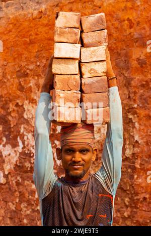 Dhaka, Dhaka, Bangladesh. 15 février 2024. Les ouvriers portent des piles de briques pesant plus de 20 kg sur la tête dans un four à Dhaka, au Bangladesh. Les ouvriers ''“ qui sont payés moins de Â£ 1 par quart ''“ se déplacent jusqu'à 2 500 briques par jour dans des conditions étouffantes. Environ 4 00 000 migrants à faible revenu arrivent à Dacca en provenance de différentes régions du pays chaque année pour travailler à brickfields. Les longues heures de travail sous le soleil brûlant dans les champs de briques, l'accumulation massive de poussière, le risque de tomber des camions et des piles de briques, et le transport de charges excessives posent de graves risques pour la santé du W. Banque D'Images