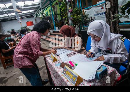 Fonctionnaires électoraux portant des uniformes d'école secondaire dans un bureau de vote, lors des élections générales à Bogor, Indonésie, le 14 février 2024 Banque D'Images