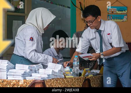 Fonctionnaires électoraux portant des uniformes d'école secondaire dans un bureau de vote, lors des élections générales à Bogor, Indonésie, le 14 février 2024 Banque D'Images