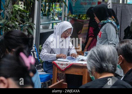 Fonctionnaires électoraux portant des uniformes d'école secondaire dans un bureau de vote, lors des élections générales à Bogor, Indonésie, le 14 février 2024 Banque D'Images