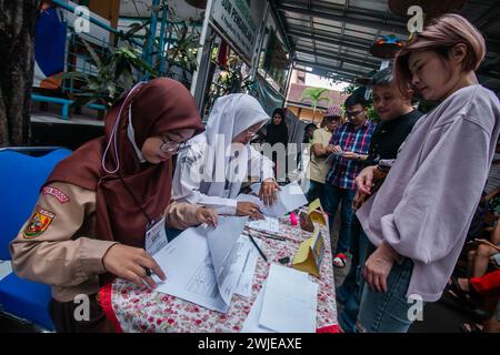 Fonctionnaires électoraux portant des uniformes d'école secondaire dans un bureau de vote, lors des élections générales à Bogor, Indonésie, le 14 février 2024 Banque D'Images