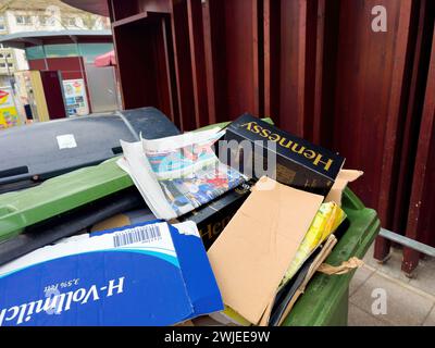 Francfort, Allemagne - 28 décembre 2023 : un bac de recyclage débordant avec divers articles jetés dans une rue urbaine. Banque D'Images