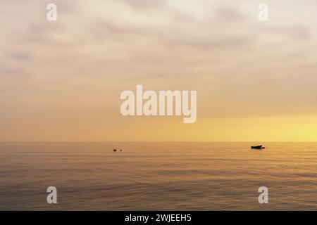 Un petit bateau à Nachor dans un océan calme au coucher du soleil Banque D'Images