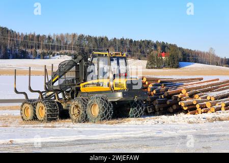 Porteur forestier Ponsse Wise avec chaînes à neige sur pneus et grumes de pin empilées sur un chantier glacé en hiver. Salo, Finlande. 9 février 2024. Banque D'Images