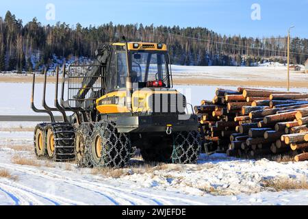 Porteur forestier Ponsse Wise avec chaînes à neige sur pneus et grumes de pin empilées sur un chantier glacé en hiver. Salo, Finlande. 9 février 2024. Banque D'Images