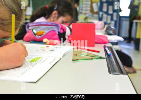 Arvieux, département des Hautes-Alpes (Alpes françaises), Queyras : classe primaire. Écolière assise à son bureau, écrivant dans son cahier d'exercices. Banque D'Images