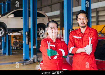 Portrait L'équipe de mécaniciens masculins japonais asiatiques dans le centre d'entretien de voiture d'atelier de service automatique remplace la pièce de moteur automatique fixe Banque D'Images