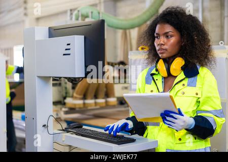 Les femmes noires africaines travaillent avec l'industrie de l'usine de meubles de machine de coupe de bois avec combinaison de sécurité Banque D'Images