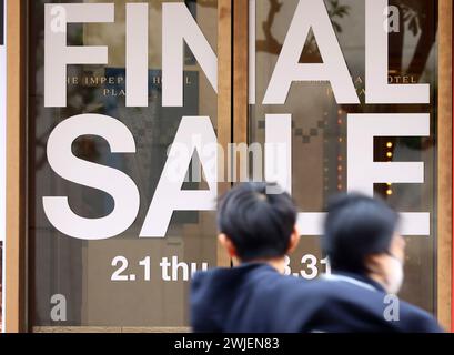 Tokyo, Japon. 15 février 2024. Les gens passent devant une boutique avec un panneau de vente à Tokyo le jeudi 15 février 2024. Le cabinet du Japon a annoncé que le produit intérieur brut (PIB) du pays s'élevait à 591,48 billions de yens (4,21 billions USD) en 2023, ce qui signifie que le Japon a perdu le titre de troisième économie mondiale contre l'Allemagne l'année dernière. (Photo de Yoshio Tsunoda/AFLO) Banque D'Images