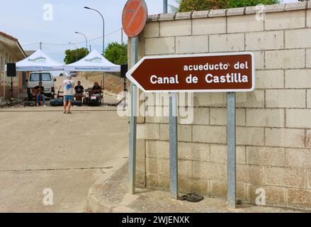Panneau routier pour un aqueduc sur le canal de Castille avec un groupe de rock jouant sous un gazebo pendant les fêtes Lantadilla Palencia Castille et Léon Espagne Banque D'Images