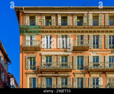 A la recherche d'appartements chics surplombant Port Lympia à Nice, sur la Côte d'Azur, France. Couleurs ocre avec volets gris-vert. Banque D'Images