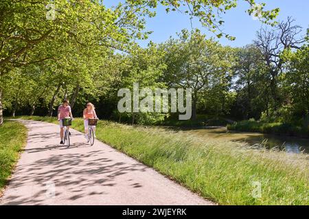 Gardouch (sud-ouest de la France) : jeune couple en balade à vélo le long des rives du canal du midi. Le canal du midi est inscrit au classement mondial H de l'UNESCO Banque D'Images