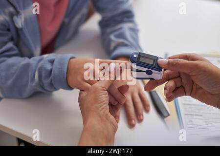 Gros plan de l'infirmière ou du médecin mettant l'oxymètre sur le doigt de l'enfant lors de l'examen médical dans l'espace de copie de la clinique Banque D'Images