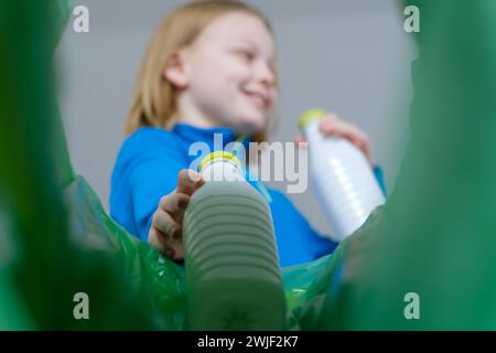 Vue à angle bas un enfant triant la corbeille en plastique à la maison. Élimination des produits de bouteilles de lait Banque D'Images