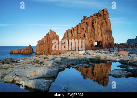 Une vue des roches rouges d'Arbatax avec des reflets dans les bassins de marée au premier plan Banque D'Images